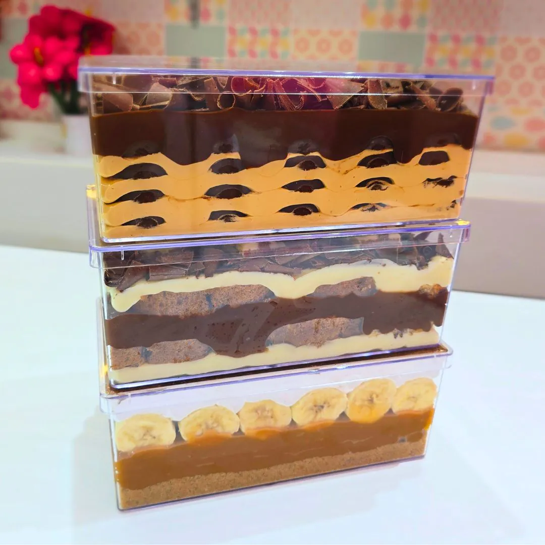 Sobremesas em travessas transparentes com camadas de chocolate, creme e banana
